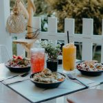 Outdoor dining setup with fresh salads and colorful drinks on a sunny day.