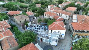 Explore a serene village in Gökçeada, Türkiye with charming red-tiled roofs and outdoor dining spaces.